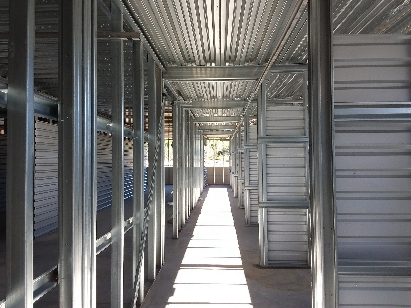 Interior corridor of metal stud framing under a steel roof deck on a commercial jobsite